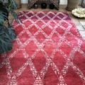 This midcentury rug is intricately handwoven in Morocco by a skilled Berber woman from the Marmoucha tribe. Featuring a striking double geometric diamond pattern against a rich red and purple background, this piece is crafted from 100% wool with a minimal pile height. In excellent condition, it boasts a remarkable pile quality that enhances its appeal.